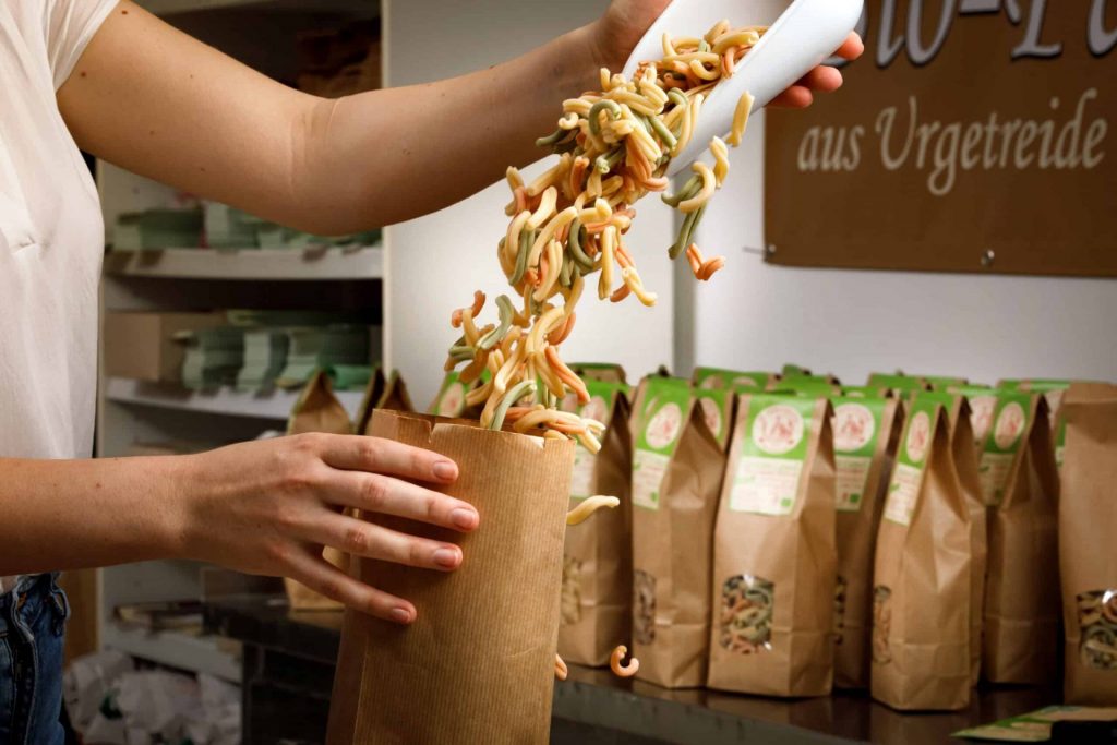 Bunte, glutenfreie Multigrain Pasta beim Verpacken, umweltfreundliche Verpackung, Qualität aus Urgetreide.