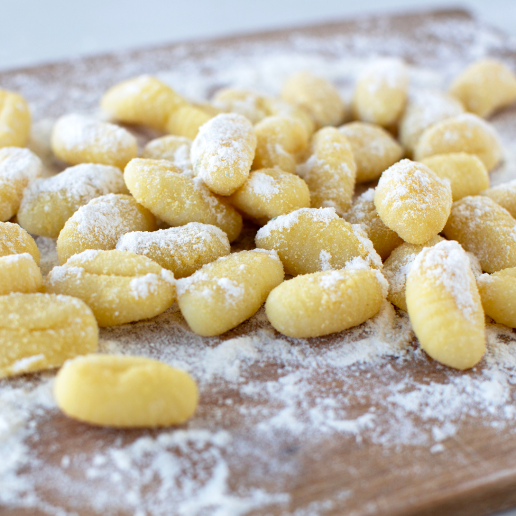 Frische Gnocchi mit Mehl bestreut auf Holzbrett.