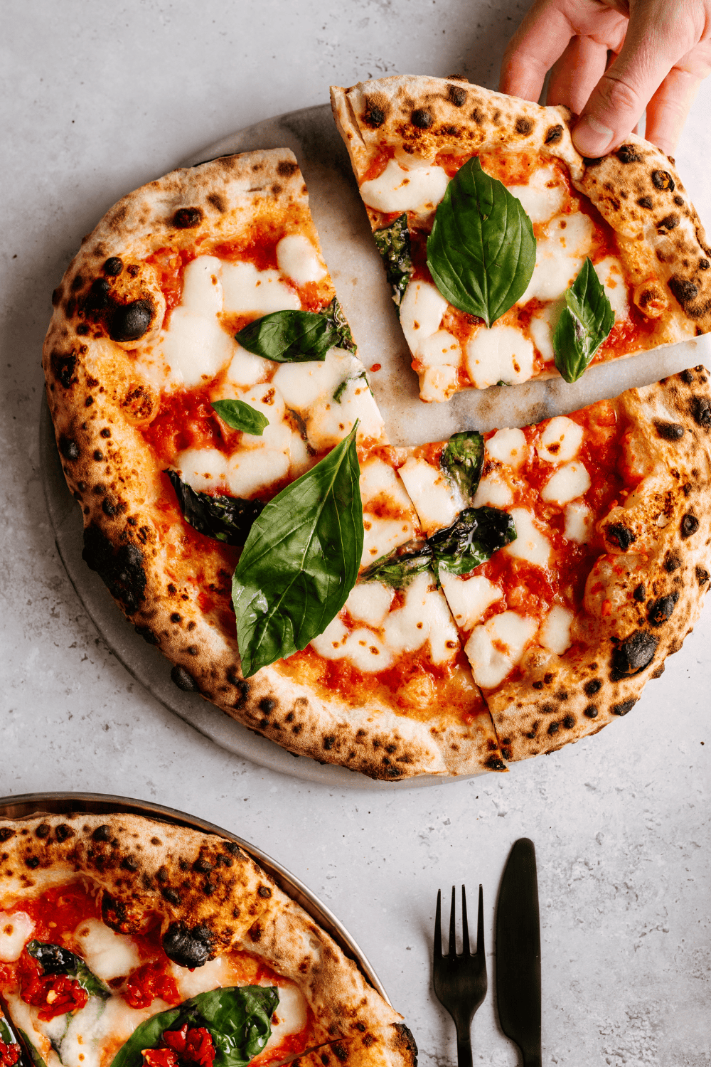 Knusprige neapolitanische pizza mit frischen basilikumblättern und geschmolzenem mozzarella, typisch italienisches essen.